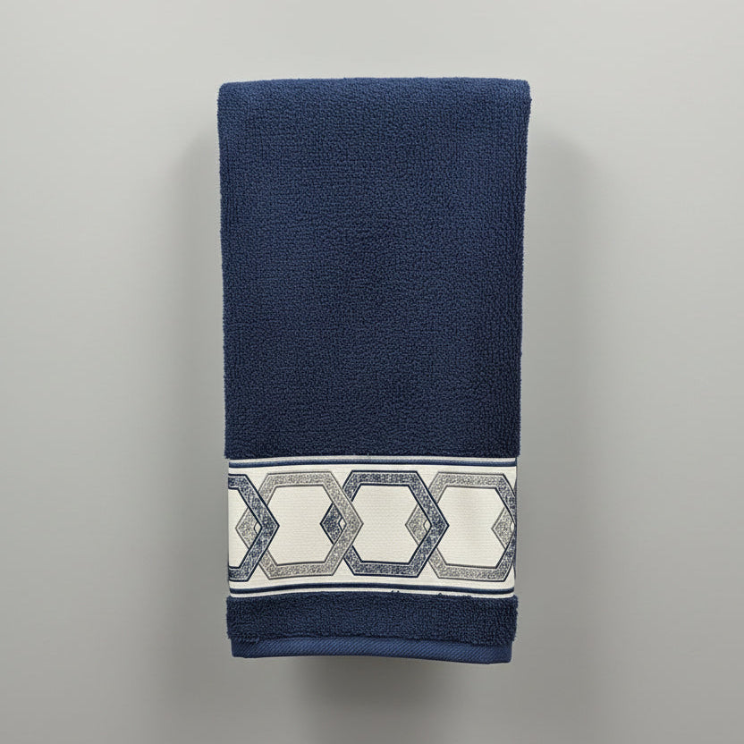 Blue towel with decorative pattern hanging on a black rack against a white tiled wall.
