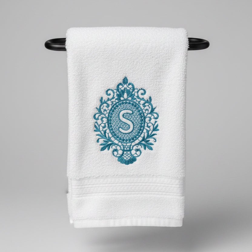 White towel with blue decorative emblem and letter 'S' on a black background