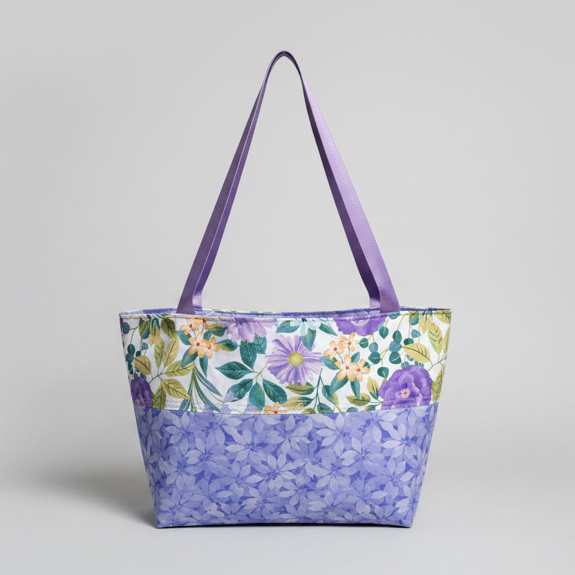 Floral-patterned tote bag with purple handles on a windowsill.