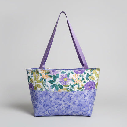 Floral-patterned tote bag with purple handles on a windowsill.