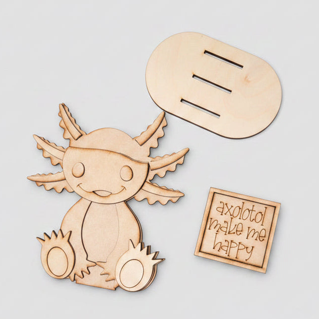 Wooden axolotl cutout with a speech bubble and a small wooden box on a brown surface.