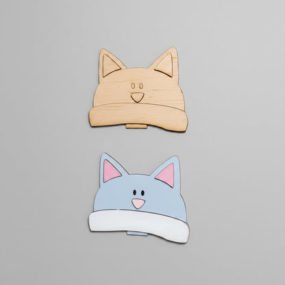 Cardboard cutout of cat-shaped boxes on a cardboard surface with additional cutouts below.
