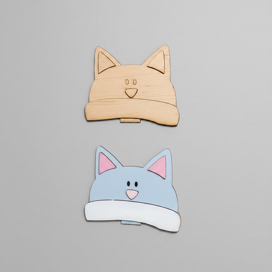 Cardboard cutout of cat-shaped boxes on a cardboard surface with additional cutouts below.