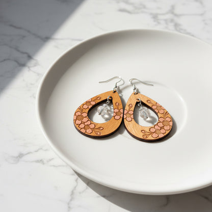 Wooden earrings with floral patterns hanging on a white plate with a marble background