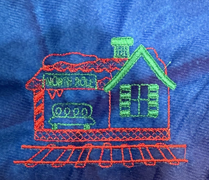 Northpole Village tree skirt with a sketch style embroidery on a blue background.