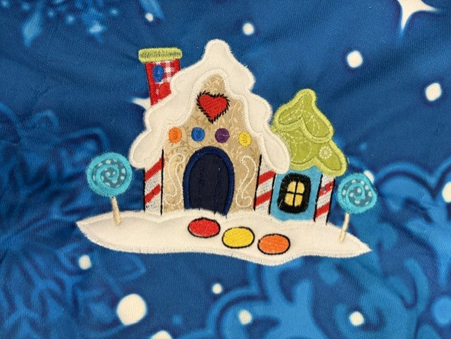 Northpole Village tree skirt with applique embroidery on a blue background.