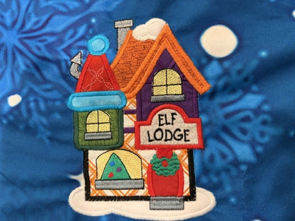 Northpole Village tree skirt with applique embroidery on a blue background.