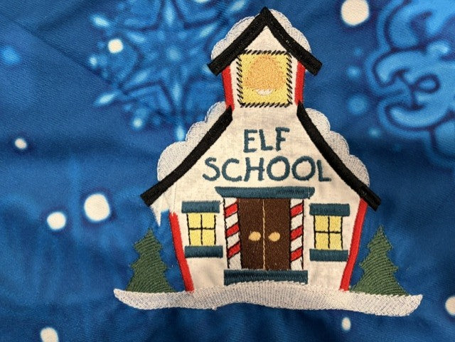 Northpole Village tree skirt with applique embroidery on a blue background.