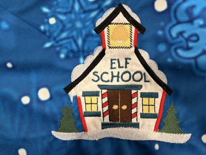 Northpole Village tree skirt with applique embroidery on a blue background.