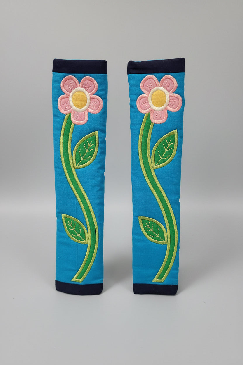 Pair of blue seat belt covers with pink flowers