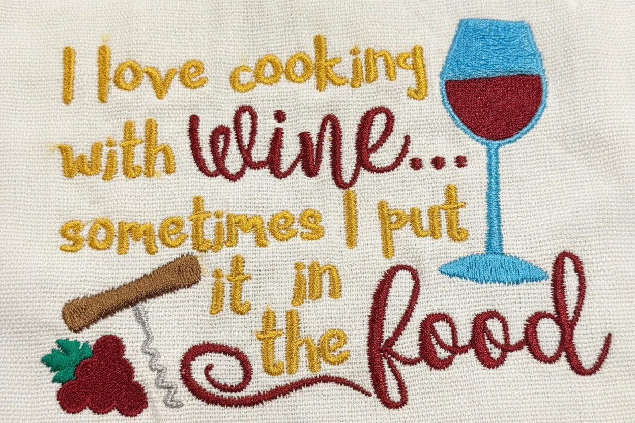 Embroidered towel with wine-themed text and graphics on a dark background