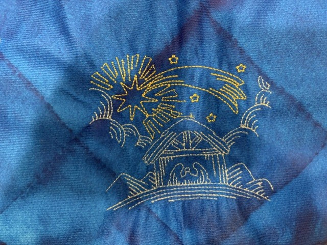 Nativity tree skirt with a blue background.