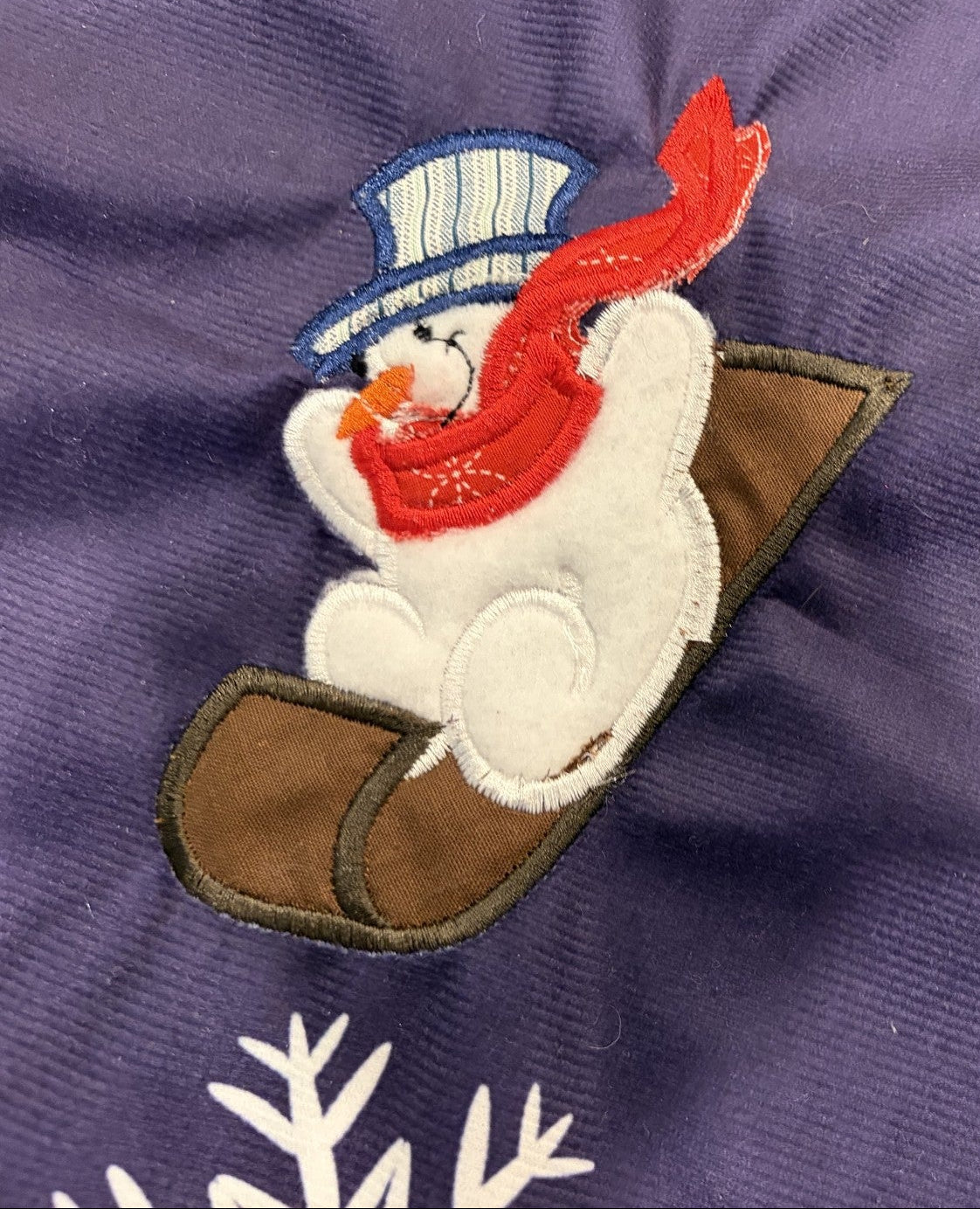 Snowmen tree skirt with applique embroidery on a blue background.