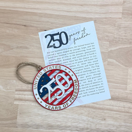 Handcrafted wooden USA 250th anniversary Christmas ornament displayed alongside its commemorative historical story card.